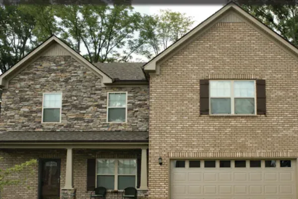 Brick home exterior with a single garage door and front entry porch.