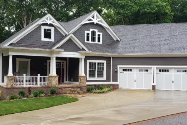 Modern home exterior with two white garage doors and a wide driveway.