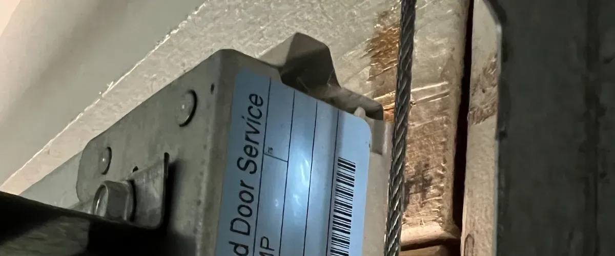 Close-up of garage door torsion spring bracket with cable