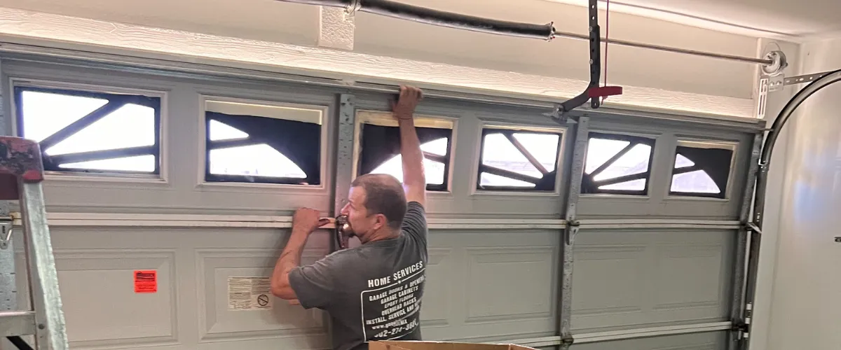 Technician aligning and securing panel of old garage door