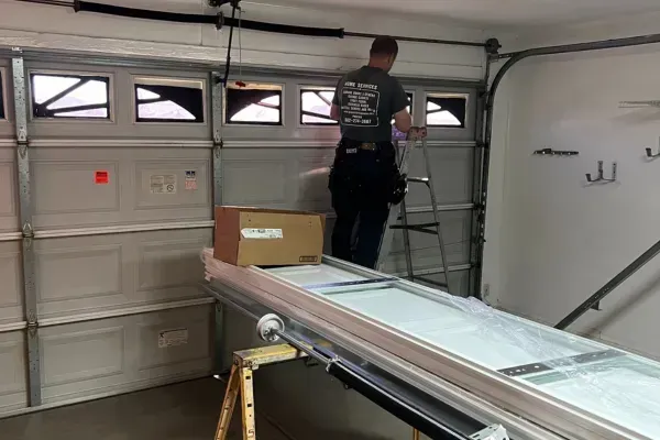 Technician on ladder adjusting garage door spring setup