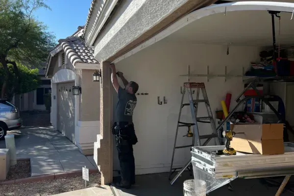 Technician securing garage door frame exterior with tools